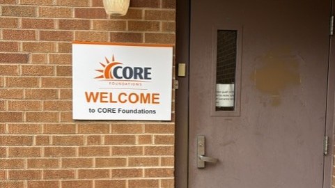The CORE Foundations welcome sign mounted on the brick wall beside our entrance door