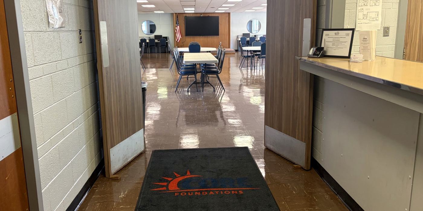 The front entrance at CORE Foundations, with the CORE Foundations logo mat in the doorway and the main activity room beyond
