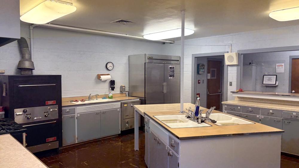 The full kitchen at CORE Foundations, with a range, commercial refrigerator, work island and prep counters