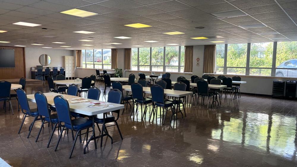 The main activity room at CORE Foundations, with tables and chairs and a wall of windows looking onto the neighborhood